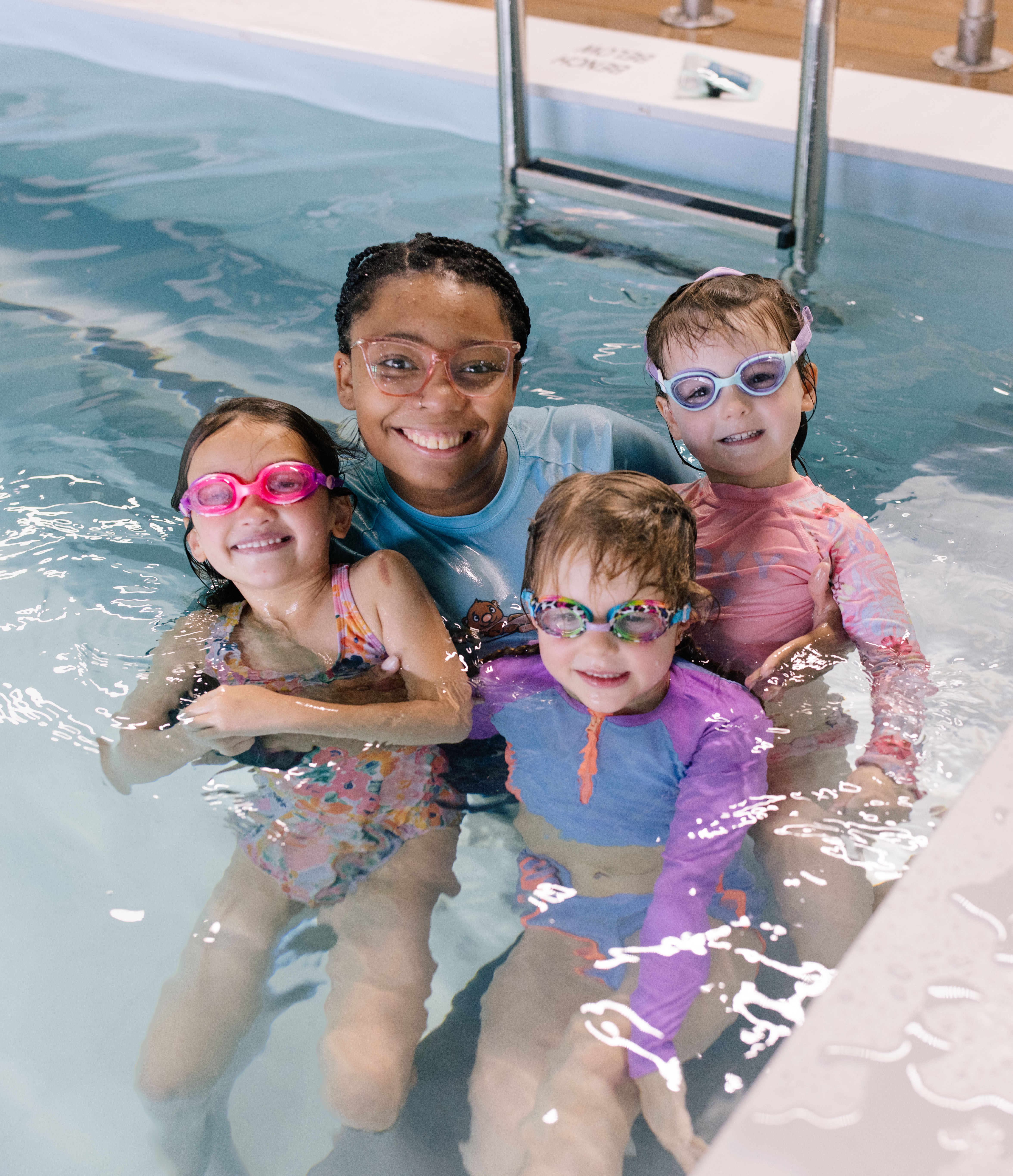 Group portrait of coach with three young swimmers