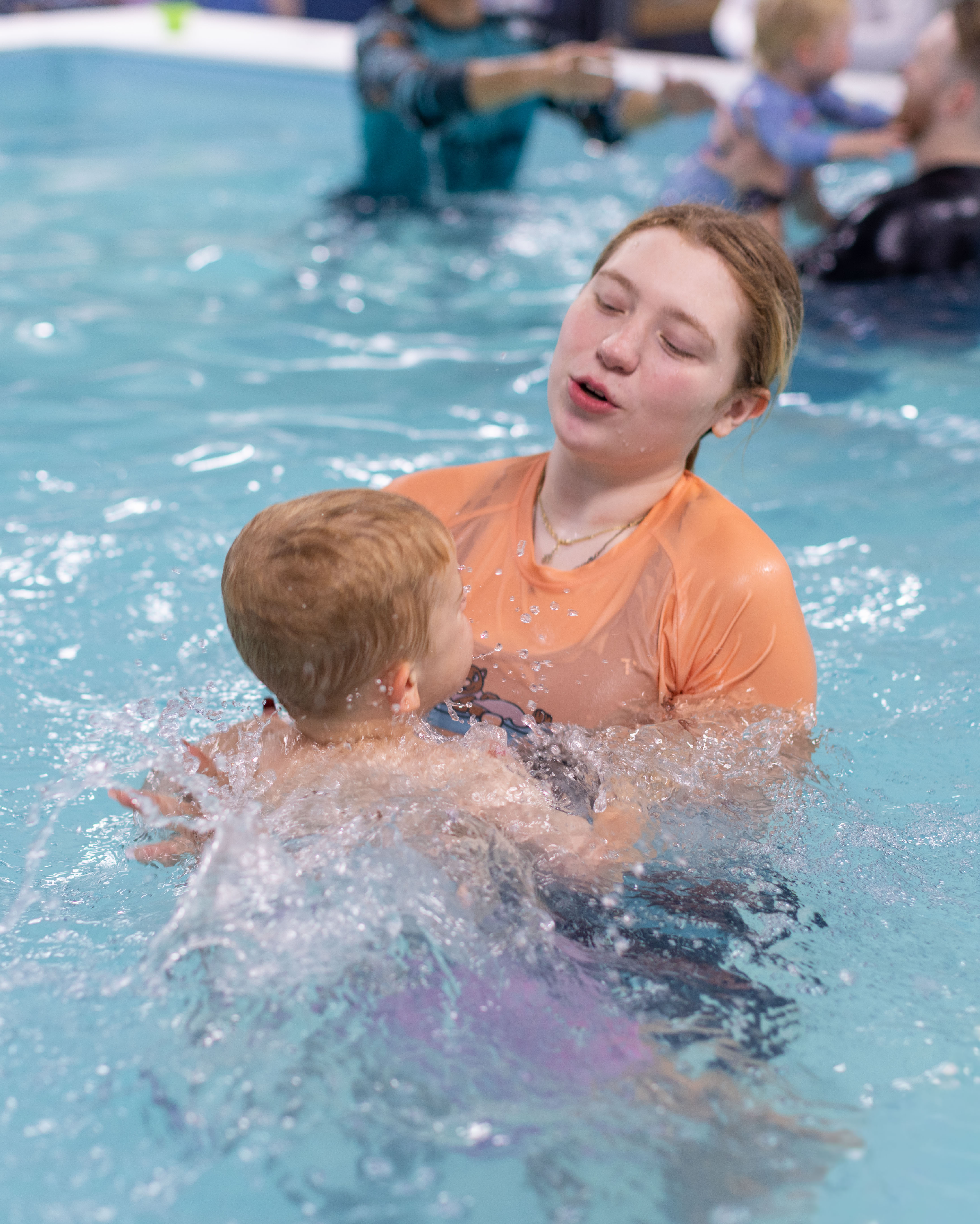 Orange-shirted instructor shares a caring 'you've got this' moment with a toddler