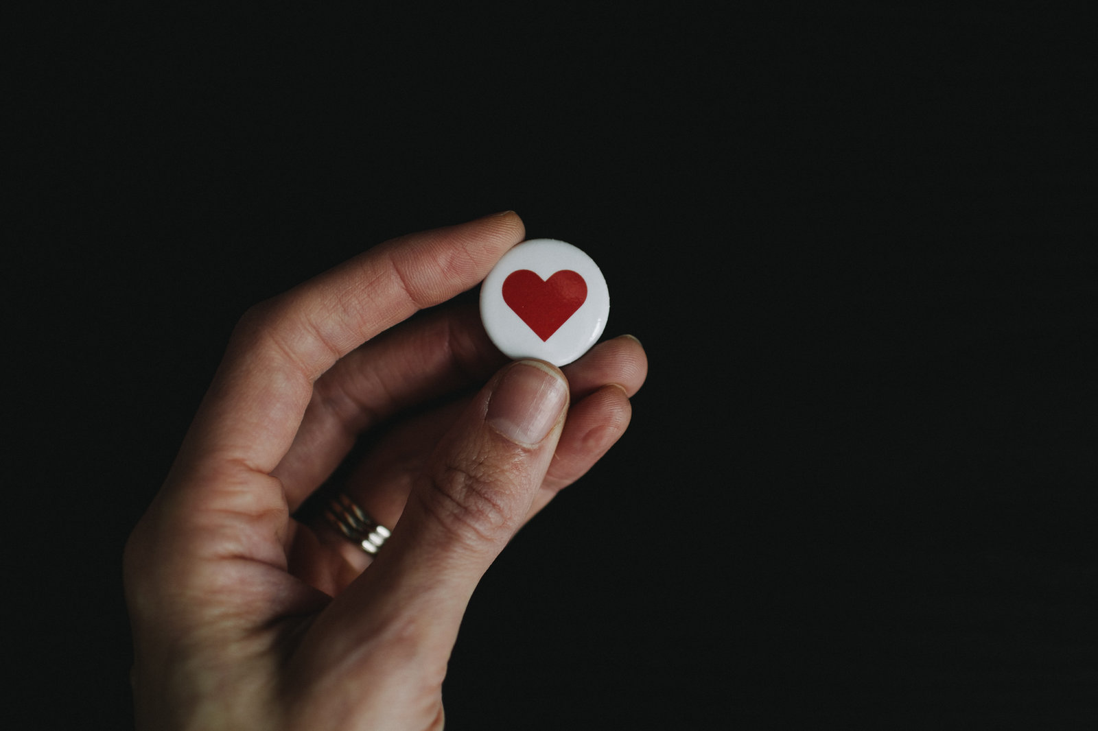 A hand holding a button with a heart on it