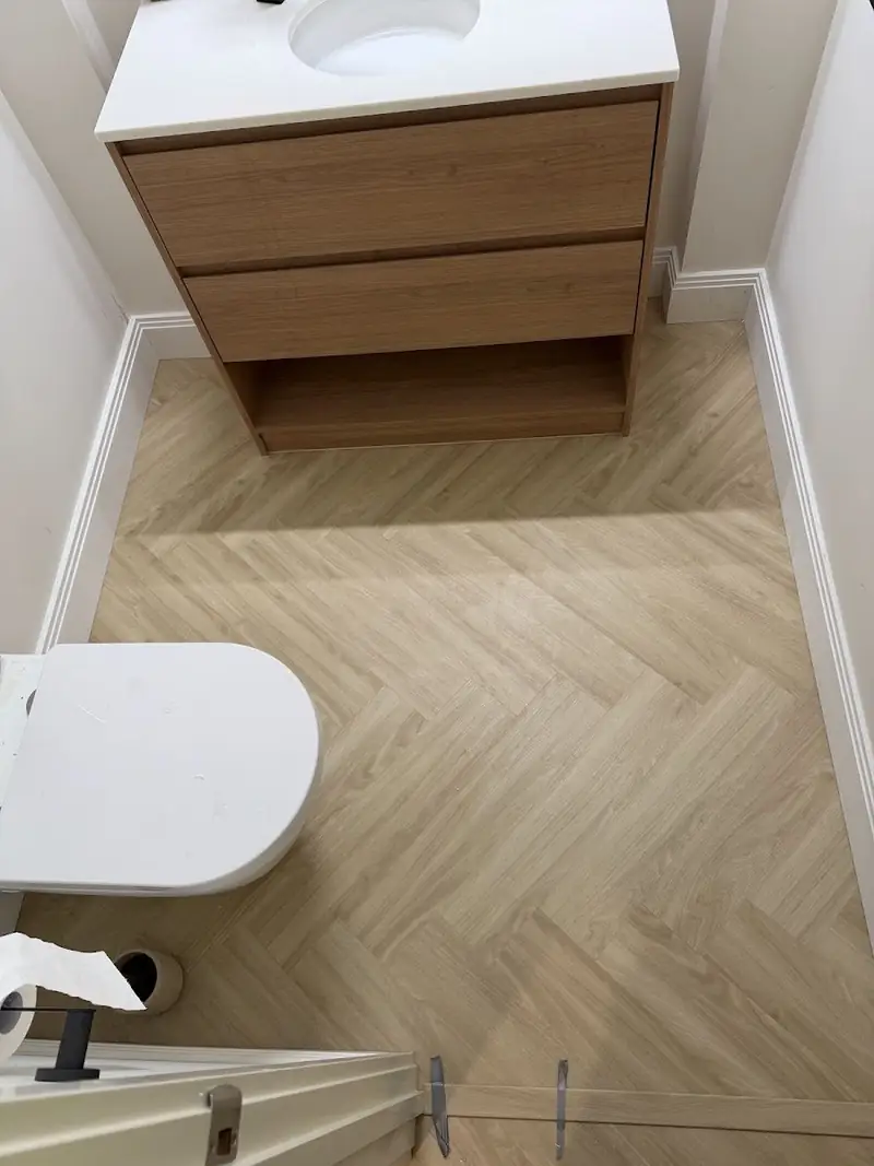 Herringbone flooring in a bathroom with vanity and toilet