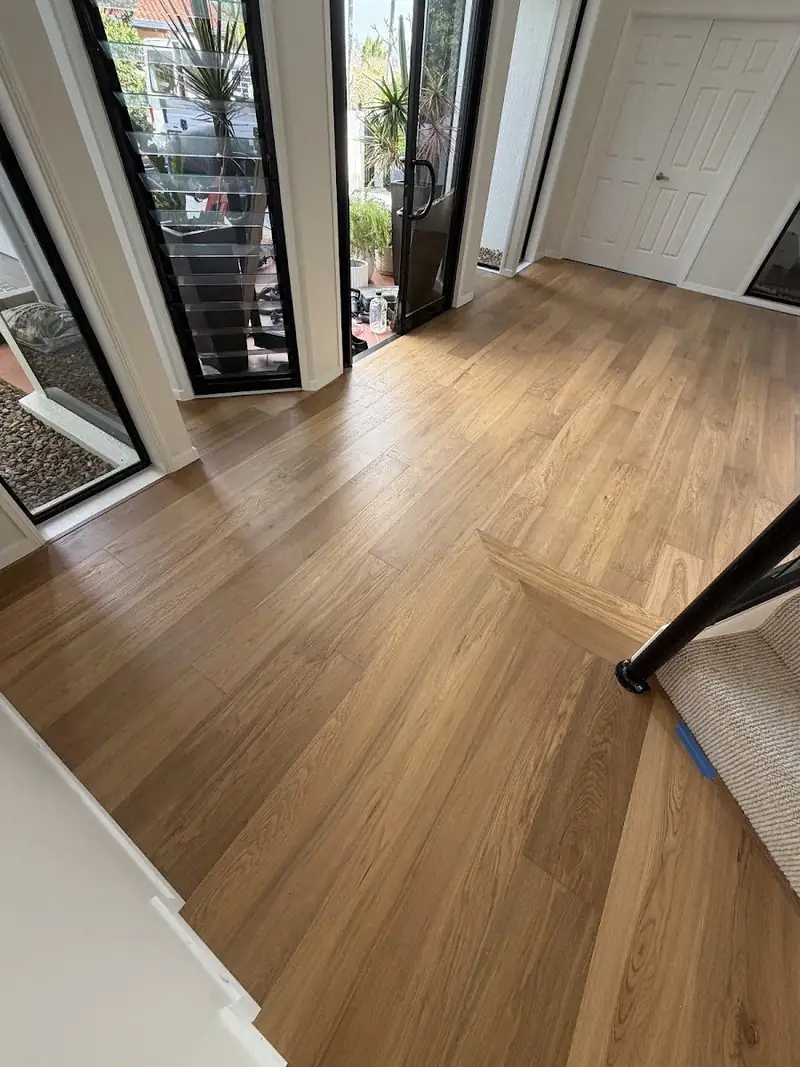 Engineered oak flooring at an entry beside a staircase with black balustrade
