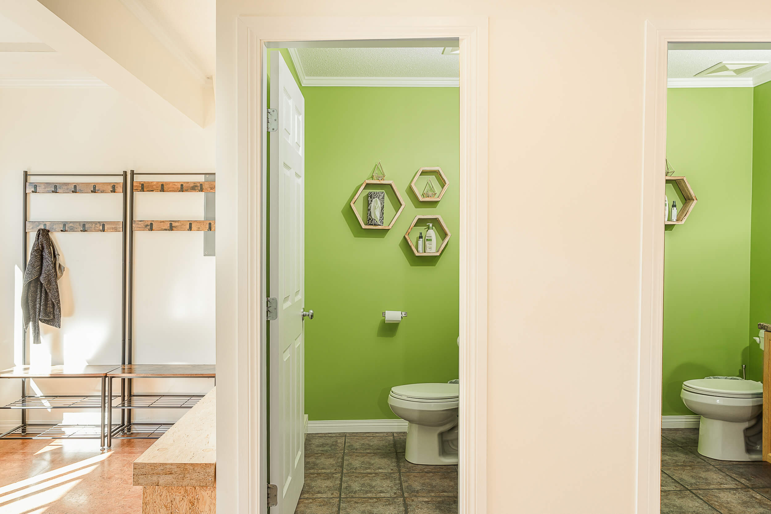 Clean and bright restroom facilities at Shala Yoga studio in Squamish with vibrant green walls, modern hexagon-shaped mirrors, and eco-friendly products on display, reflecting the studio's commitment to sustainability and comfort for its members.