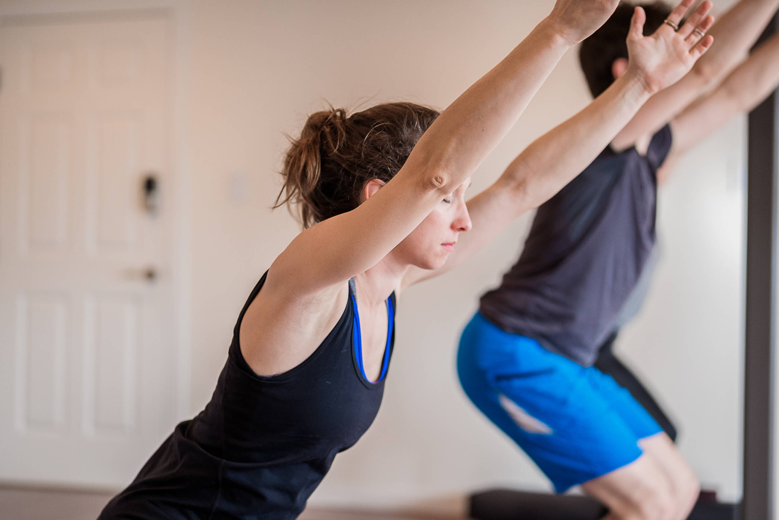 Focused participants at Shala Yoga studio in Squamish practicing Warrior I pose, highlighting the concentration and strength building aspect of yoga in a serene studio environment.
