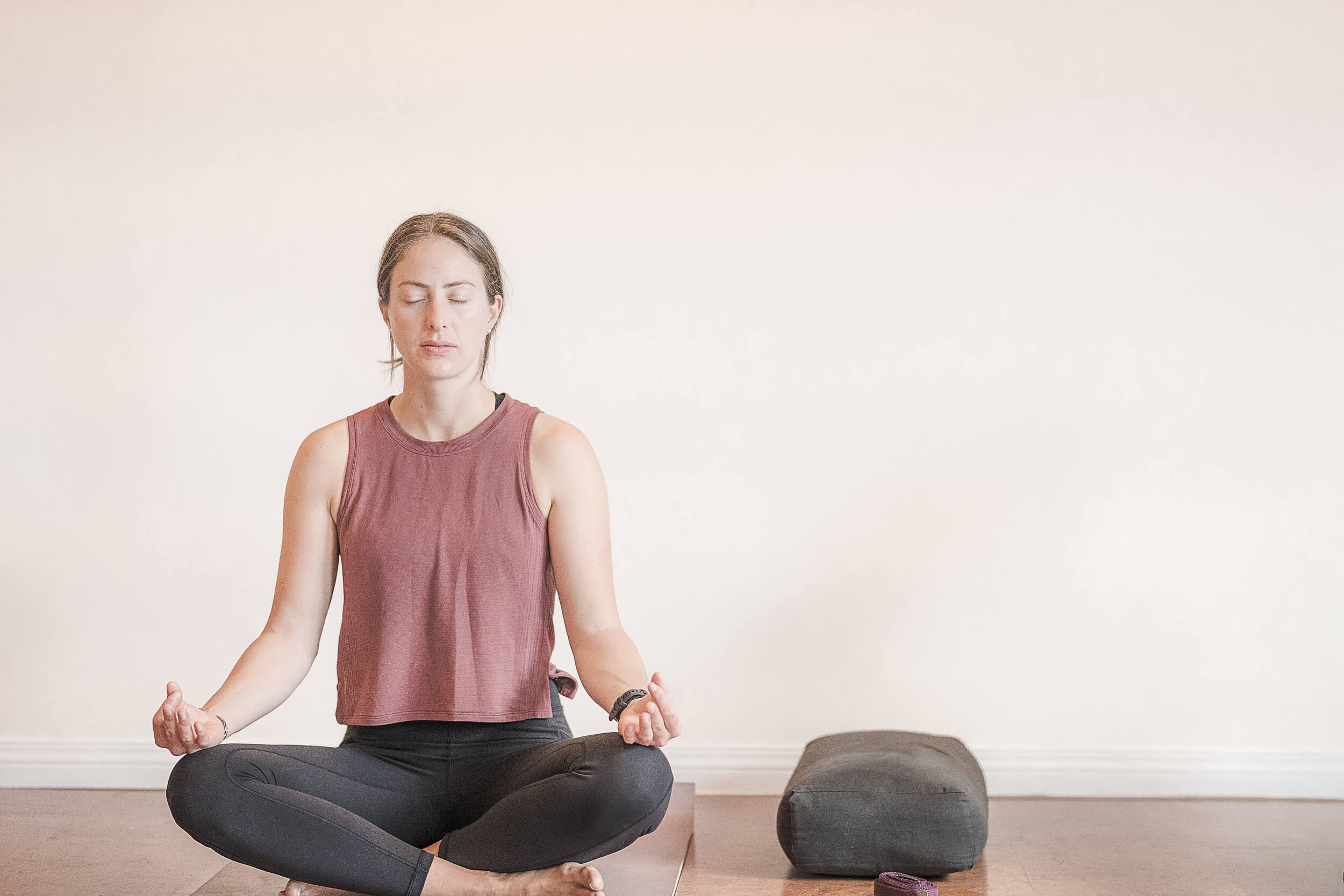 A tranquil yoga student meditates in a seated position on a mat, with eyes closed and hands resting on knees in a mudra, conveying a sense of peace and mindfulness at Shala Yoga studio in Squamish