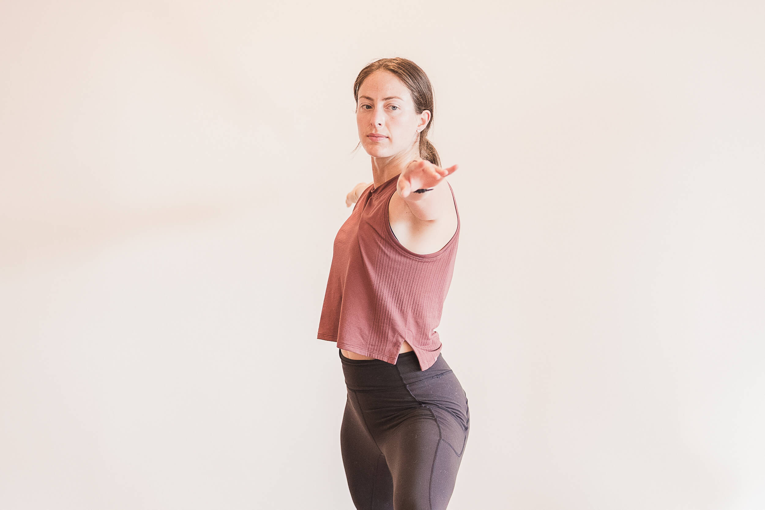 Focused yoga instructor in a standing pose with an outstretched hand towards the camera, demonstrating engagement and balance in a light-filled Shala Yoga studio in Squamish.