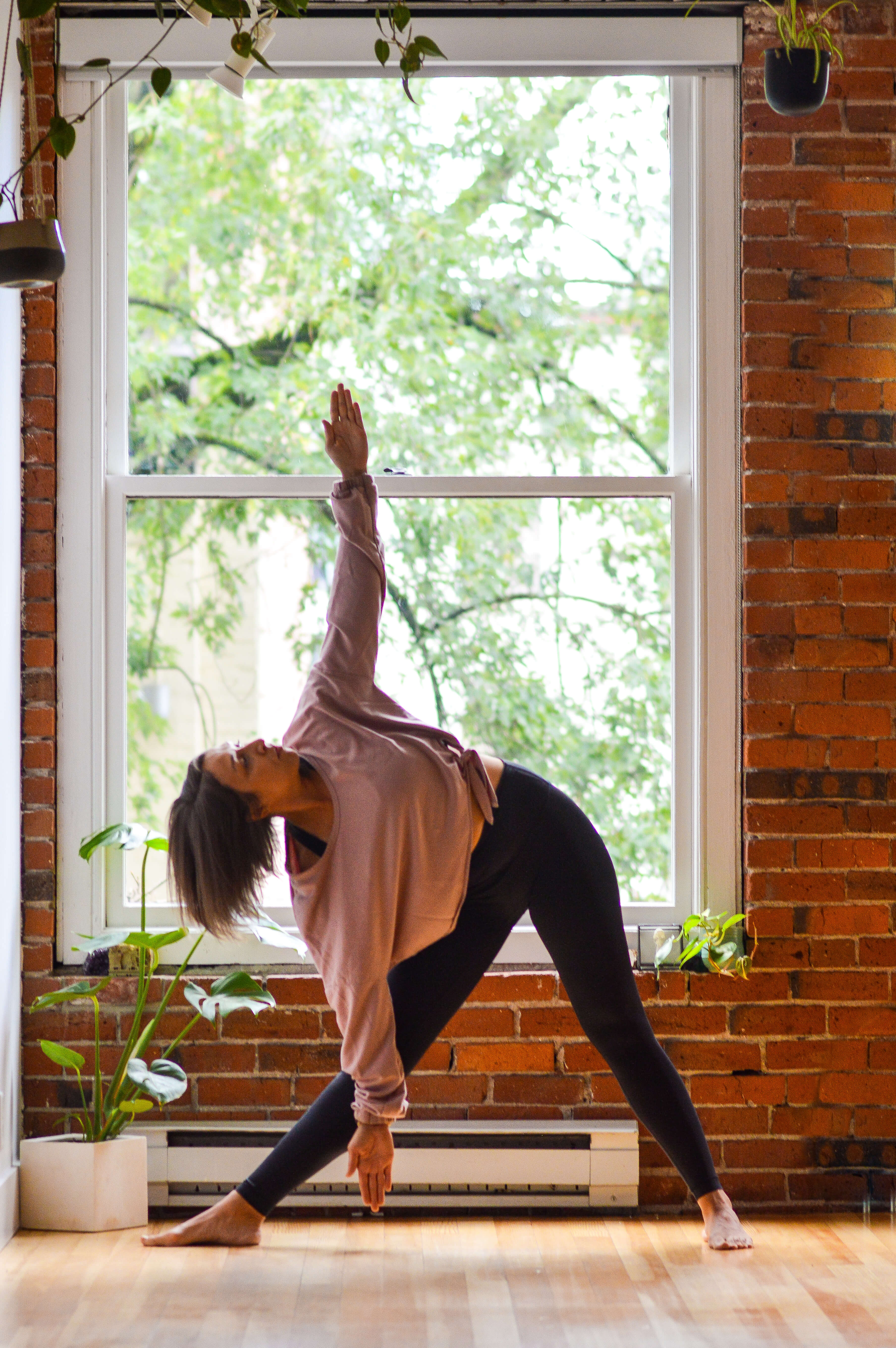 Monochrome image of a dedicated yoga instructor demonstrating an advanced split pose at Shala Yoga studio in Squamish, her tattoos adding to the artistic expression of strength and flexibility