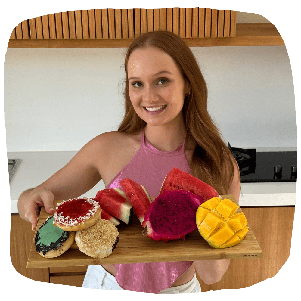 Mikaela holding a board of donuts and fresh fruit