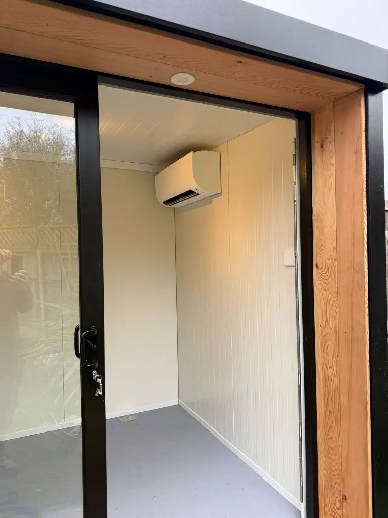 A wall unit installed in a garden room, seen through the open sliding door