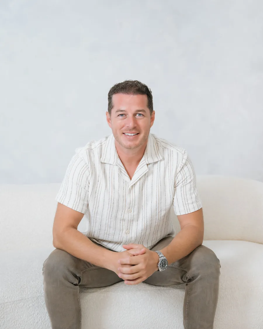 Mario Zendeli, founder of ZenMar Homes, sitting on a white couch