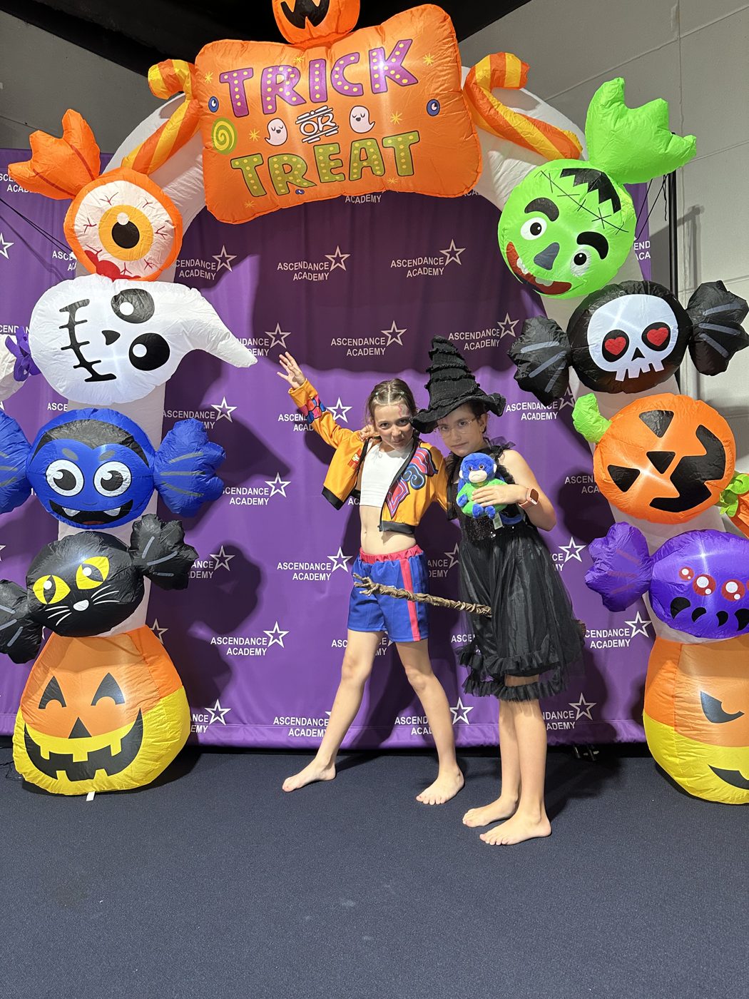 Two kids in costume posing under the Trick or Treat arch