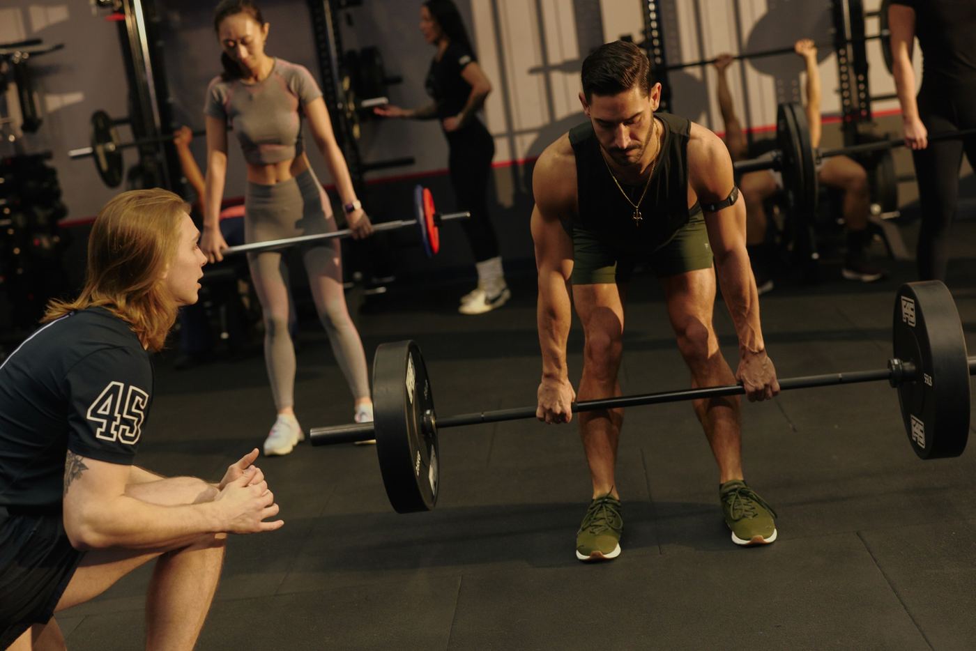 F45 coach talking a member through a barbell deadlift before the workout
