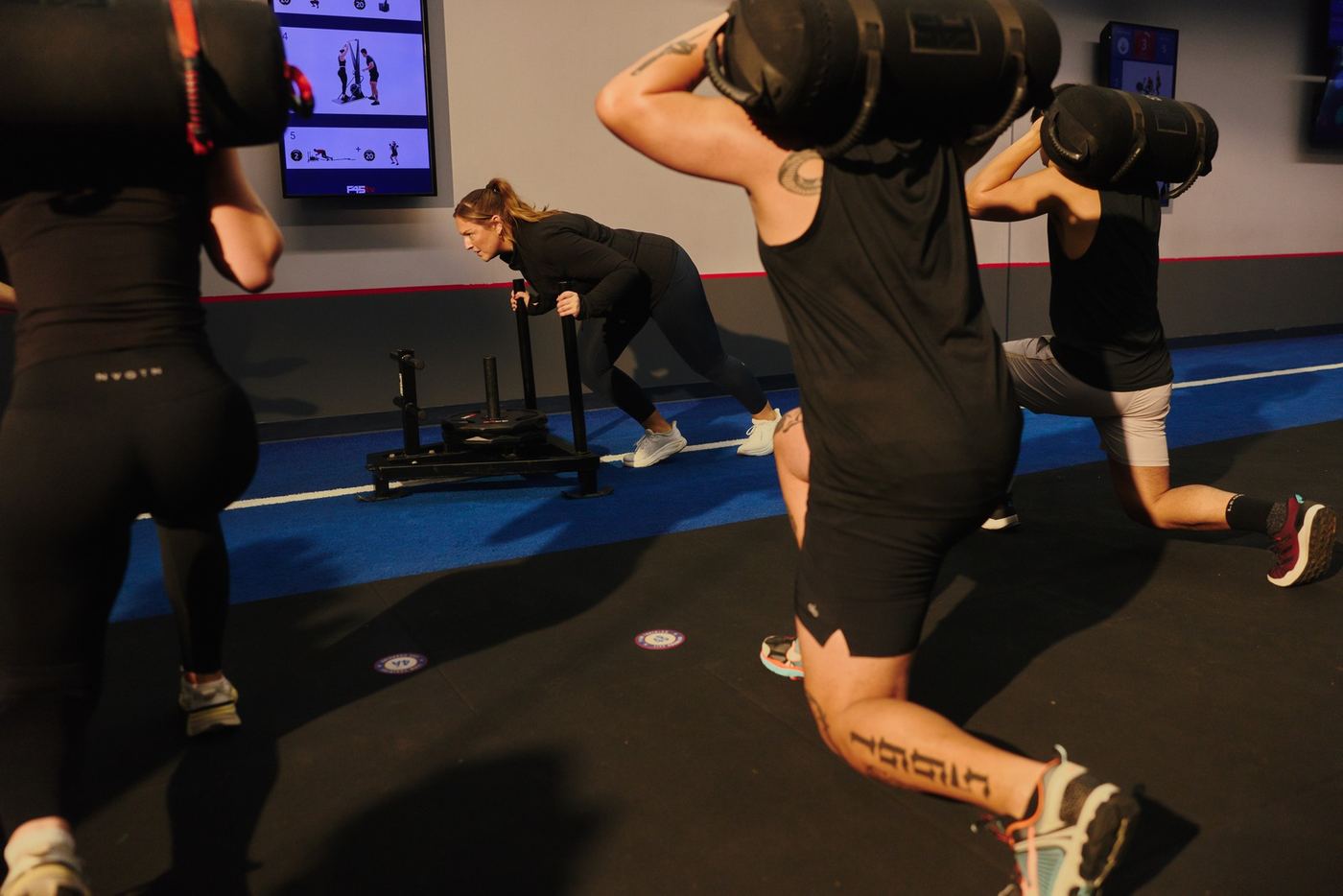 F45 members working through a sled push and sandbag lunges