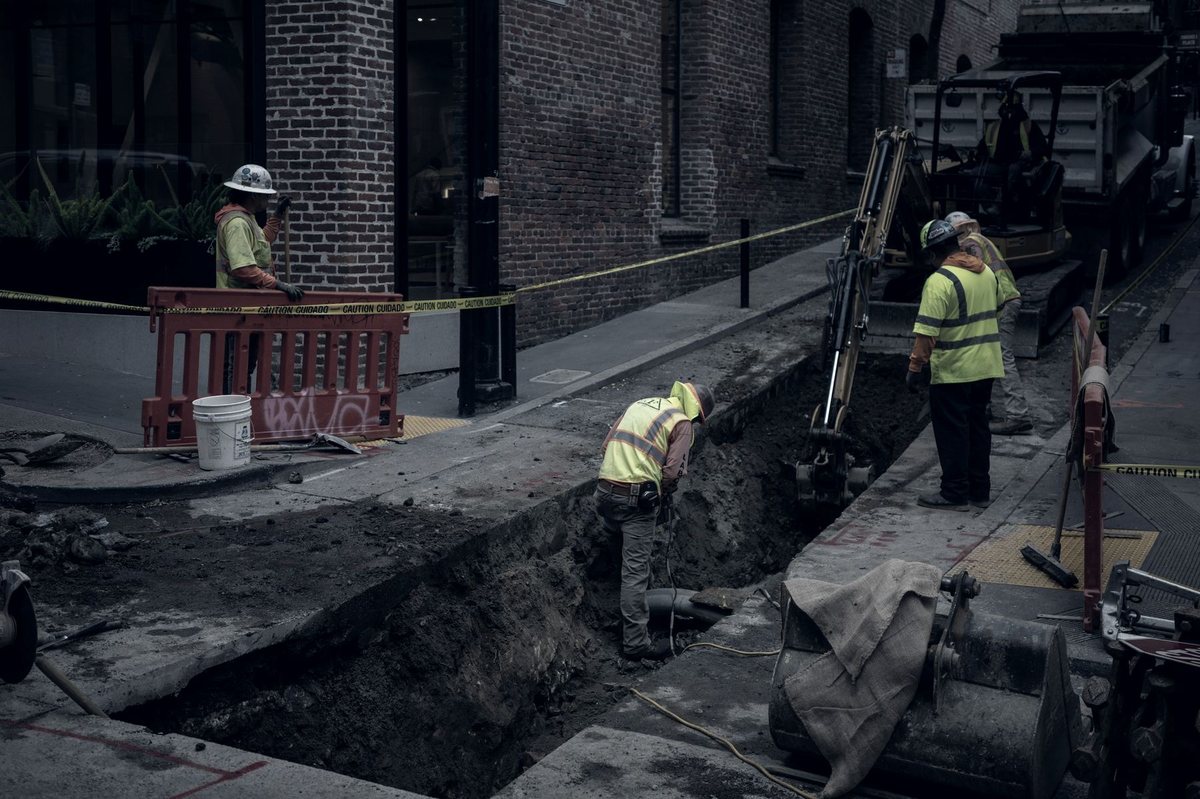 A crew in high-visibility gear excavating a utility trench
