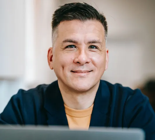 Middle-aged man smiling indoors, engaging in telehealth mental health services.