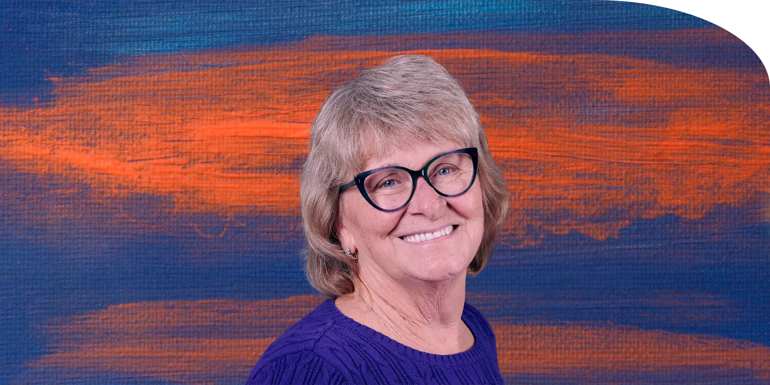 Portrait of smiling therapist in front of a colorful sunset background, representing warmth and care.