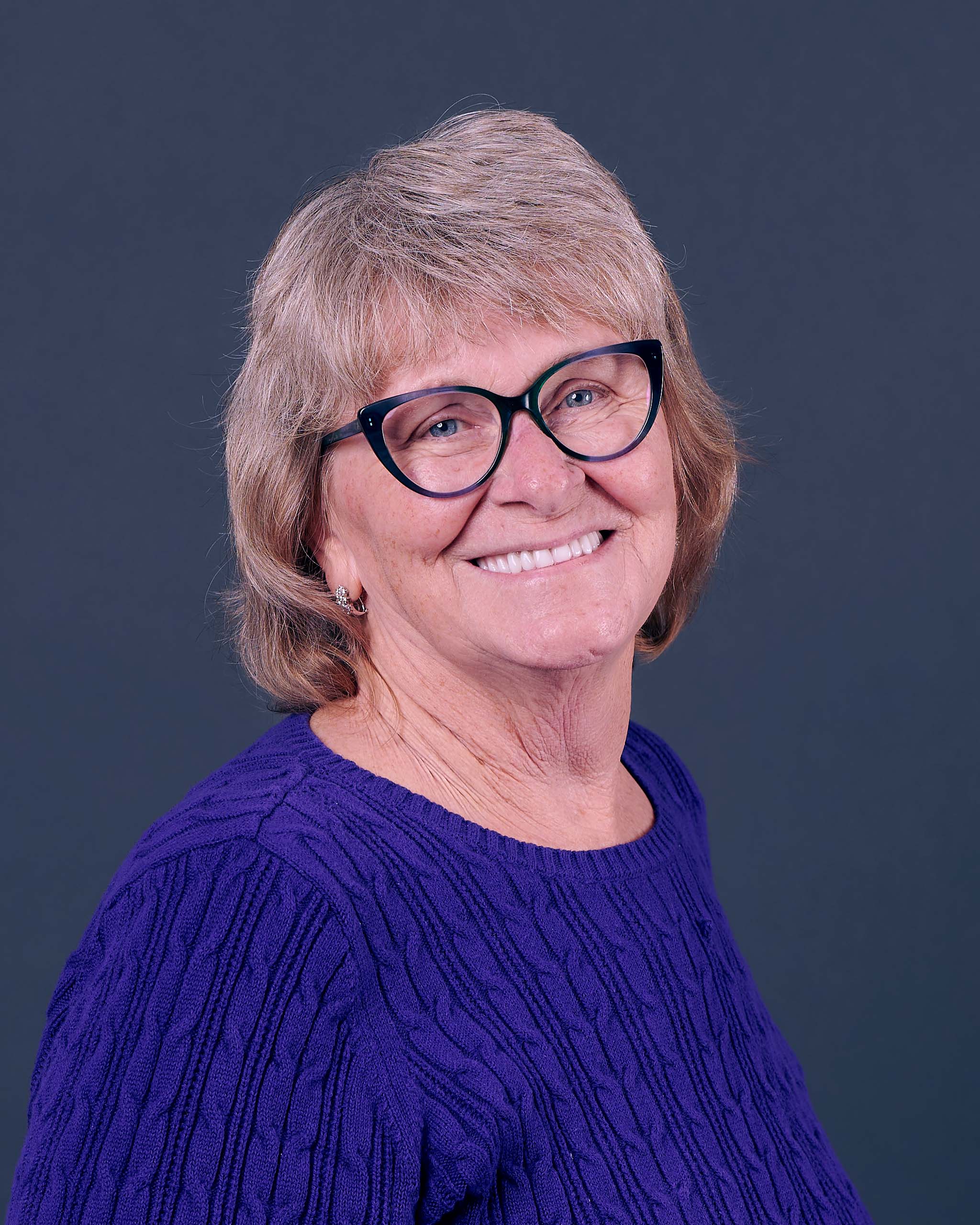 Portrait of smiling therapist in front of a colorful sunset background, representing warmth and care.