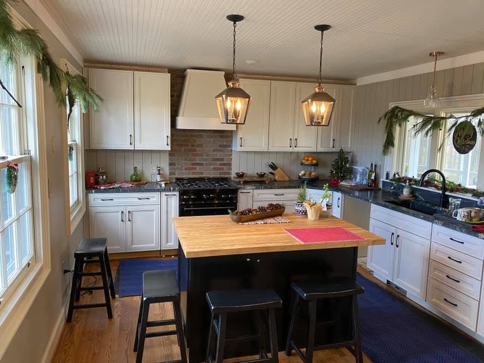 Completed kitchen with white cabinetry, brick
backsplash, dark counters, and a large island