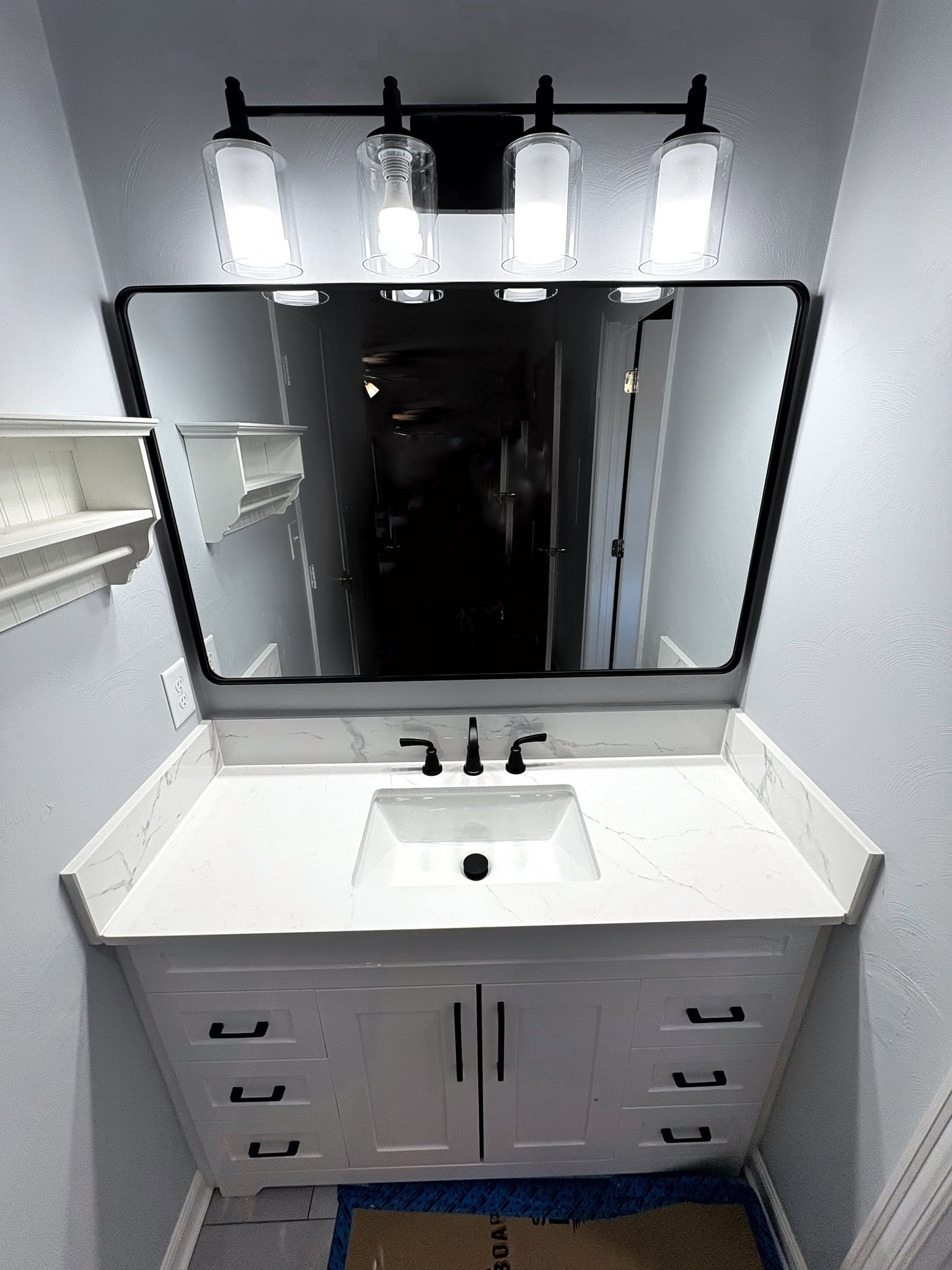 Completed bathroom vanity with white cabinetry, marble-look
countertop, and black fixtures