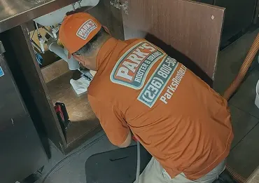 Technician clearing a clogged drain under a sink