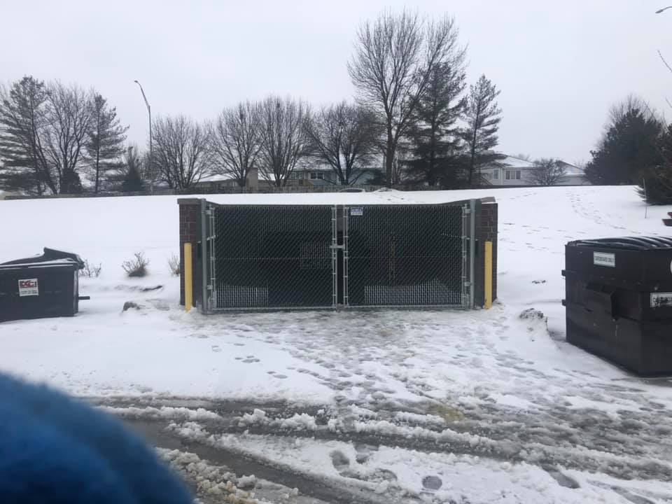 Commercial dumpster enclosure with brick pillars and chain-link gates Lincoln NE
