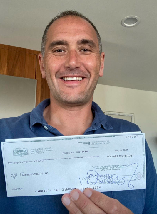 Justin Lee holding $65,000 check from ABI Investments LLC