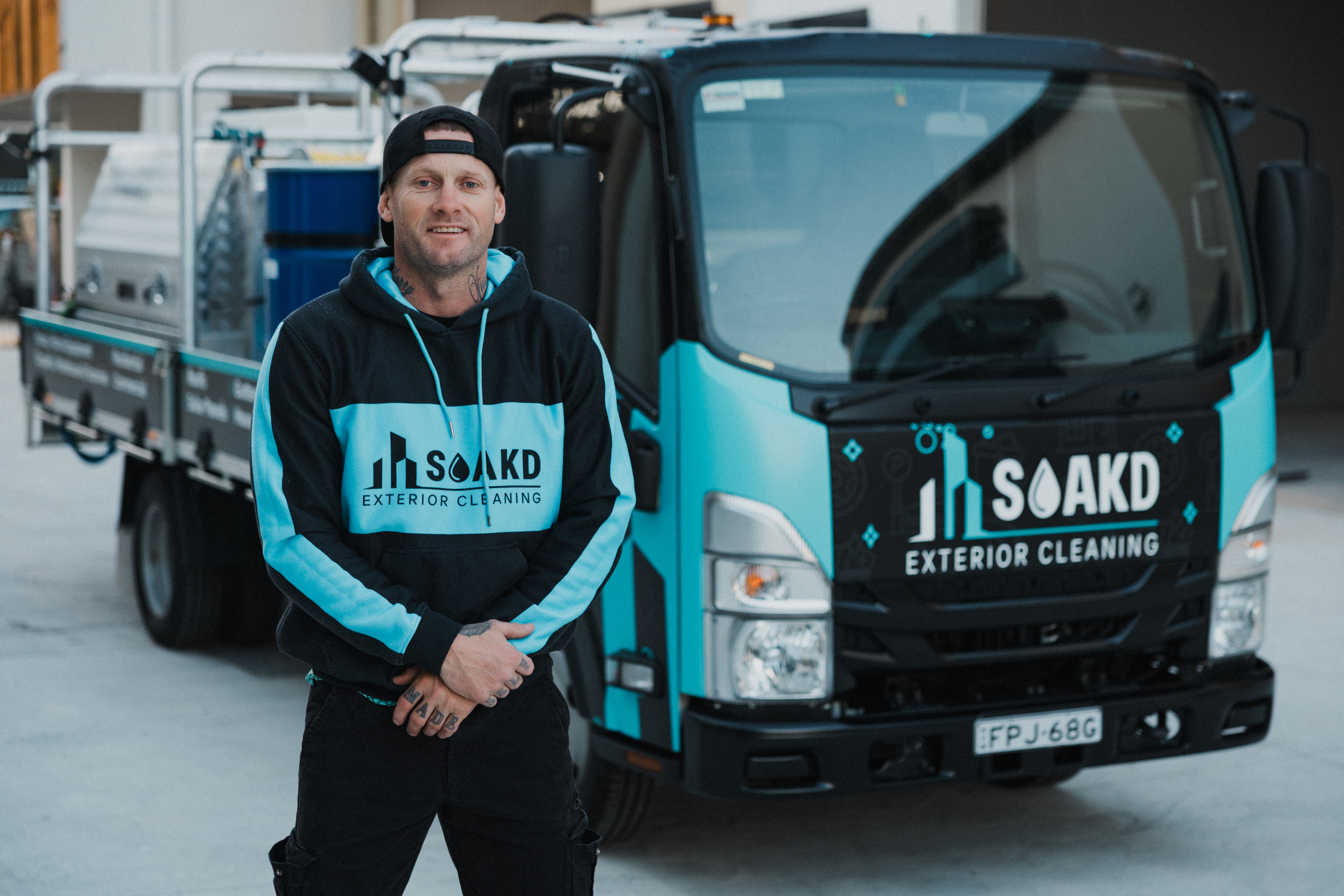 Daniel Fenton, founder of SOAKD Exterior Cleaning, standing in front of the branded SOAKD truck