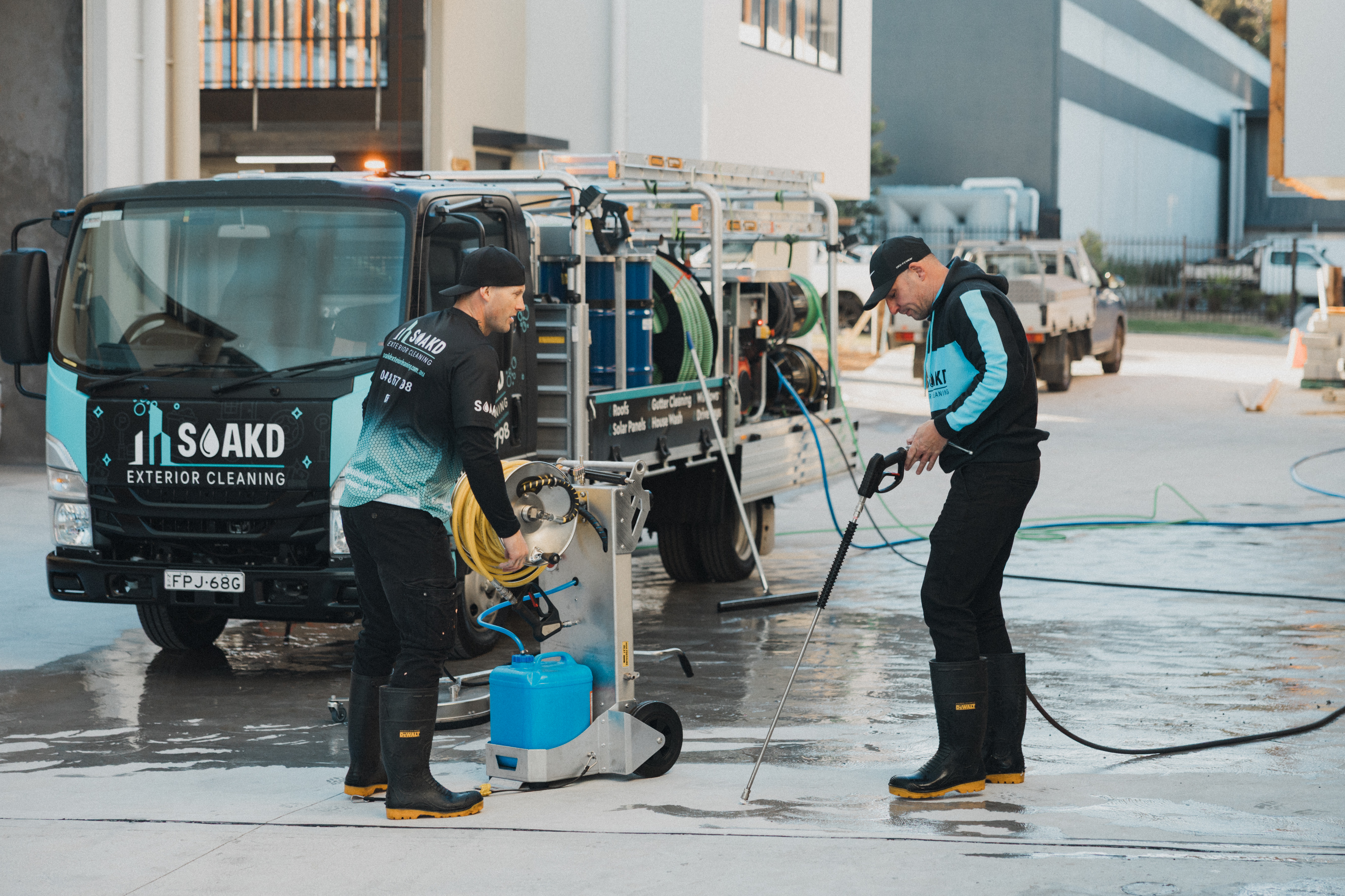 SOAKD operators preparing surface-specific cleaning equipment beside the branded truck - selecting the right method for concrete versus softwash