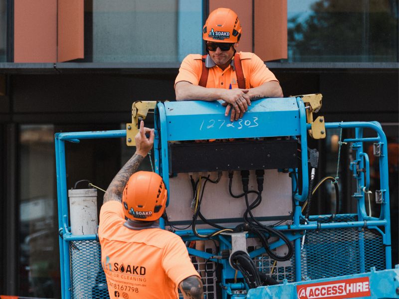 Two SOAKD operators in hi-vis safety gear conducting a safety briefing on an elevated work platform before commencing work