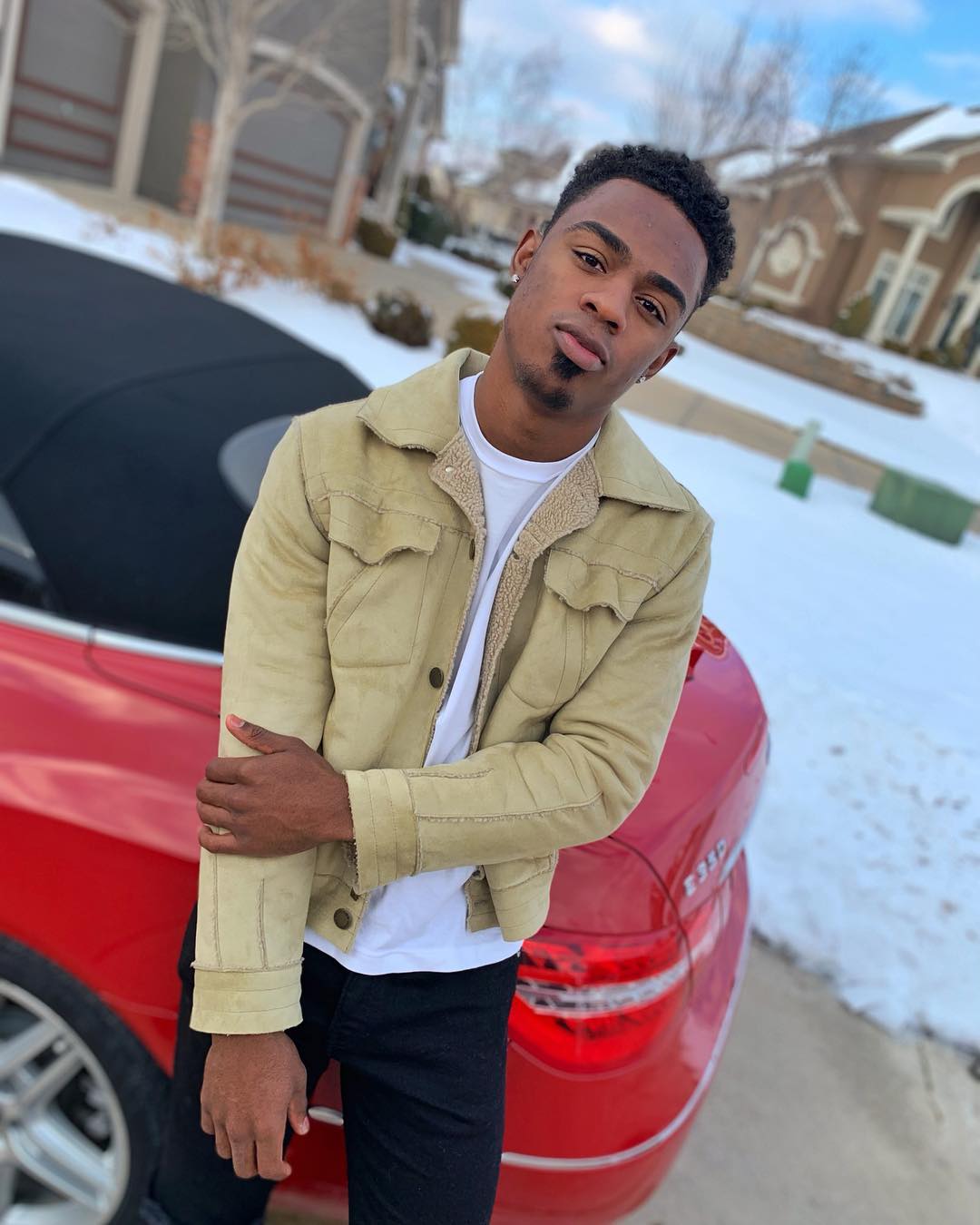 Chris in 2019, standing by a red car.