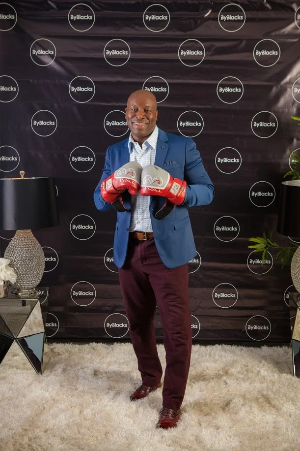 Ian Webster smiling while holding a pair of boxing gloves