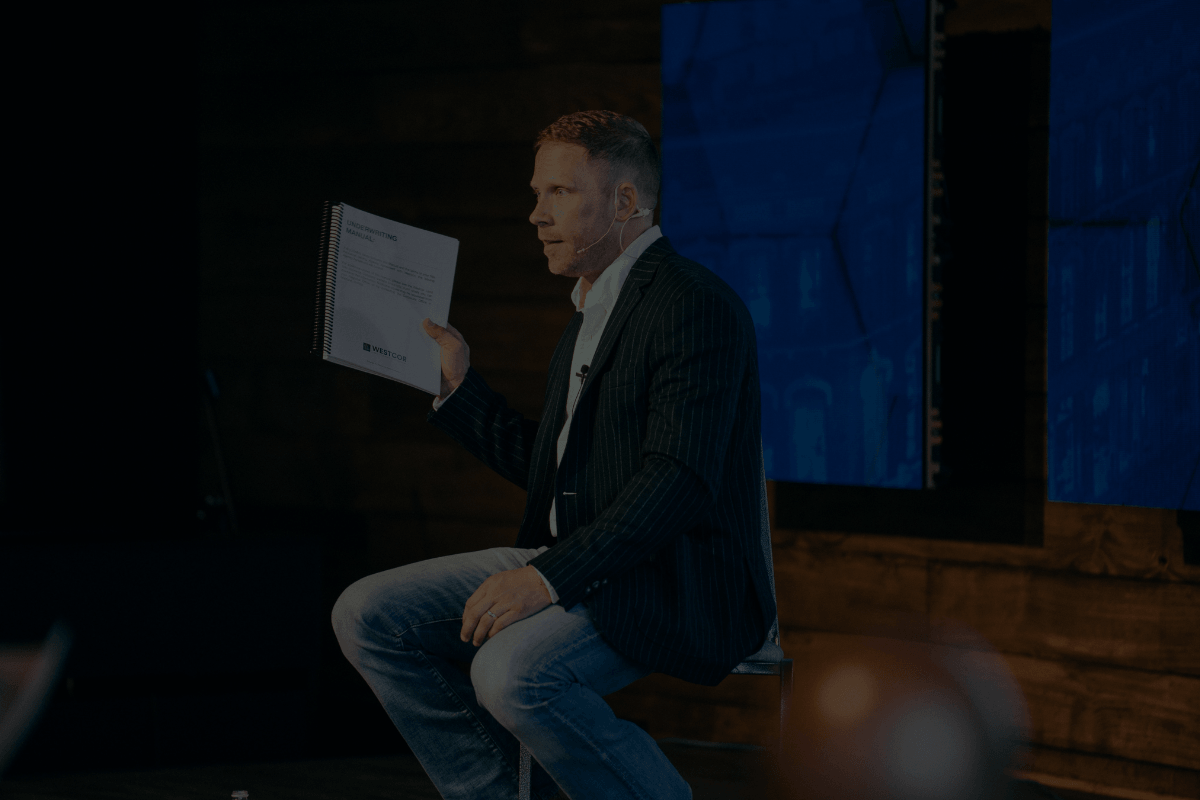 Logan Fullmer holding a real estate investing book during an event
