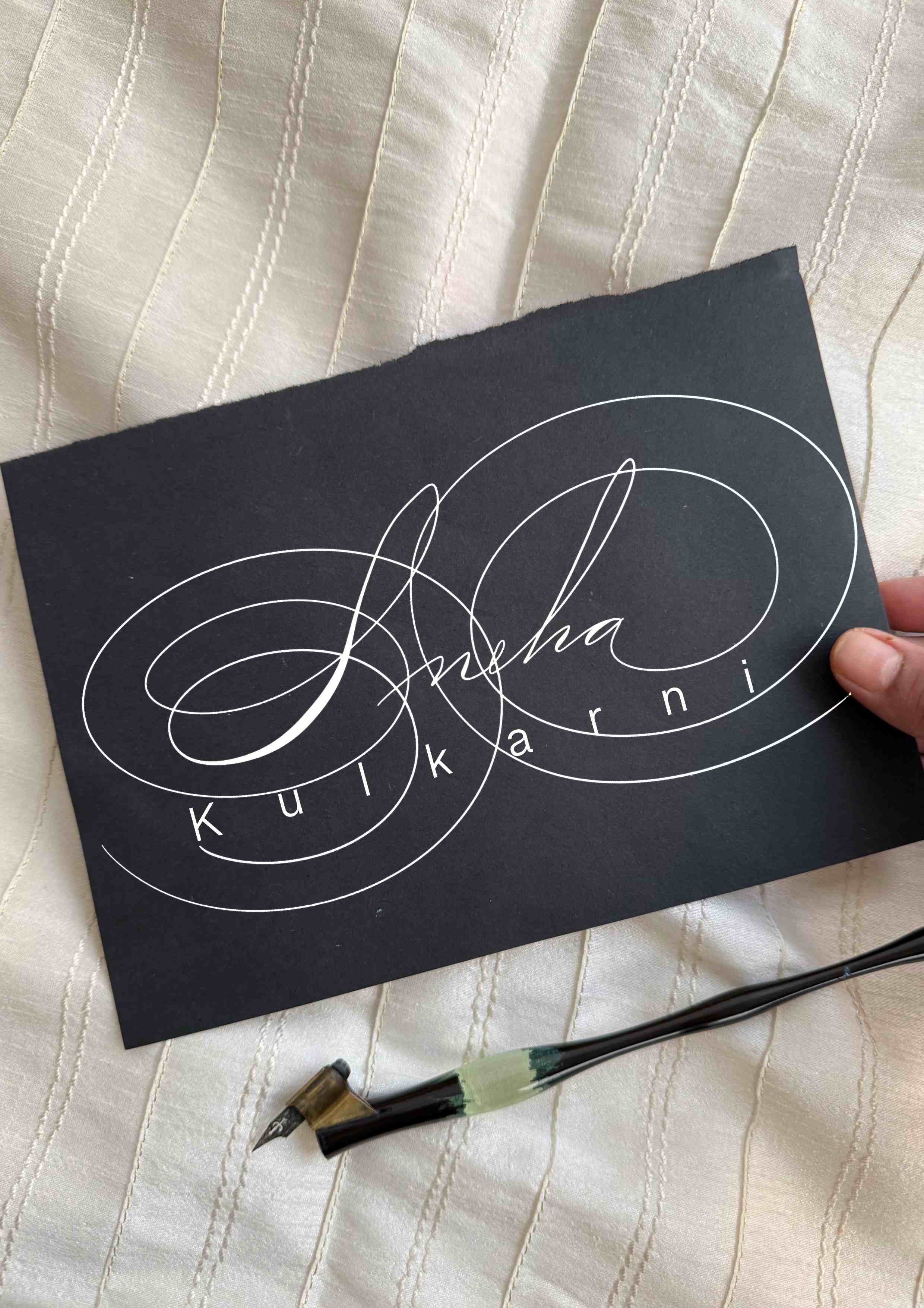 Clean Spencerian signature with light flourishing by Lavina Jhangiani, white ink on black cardstock