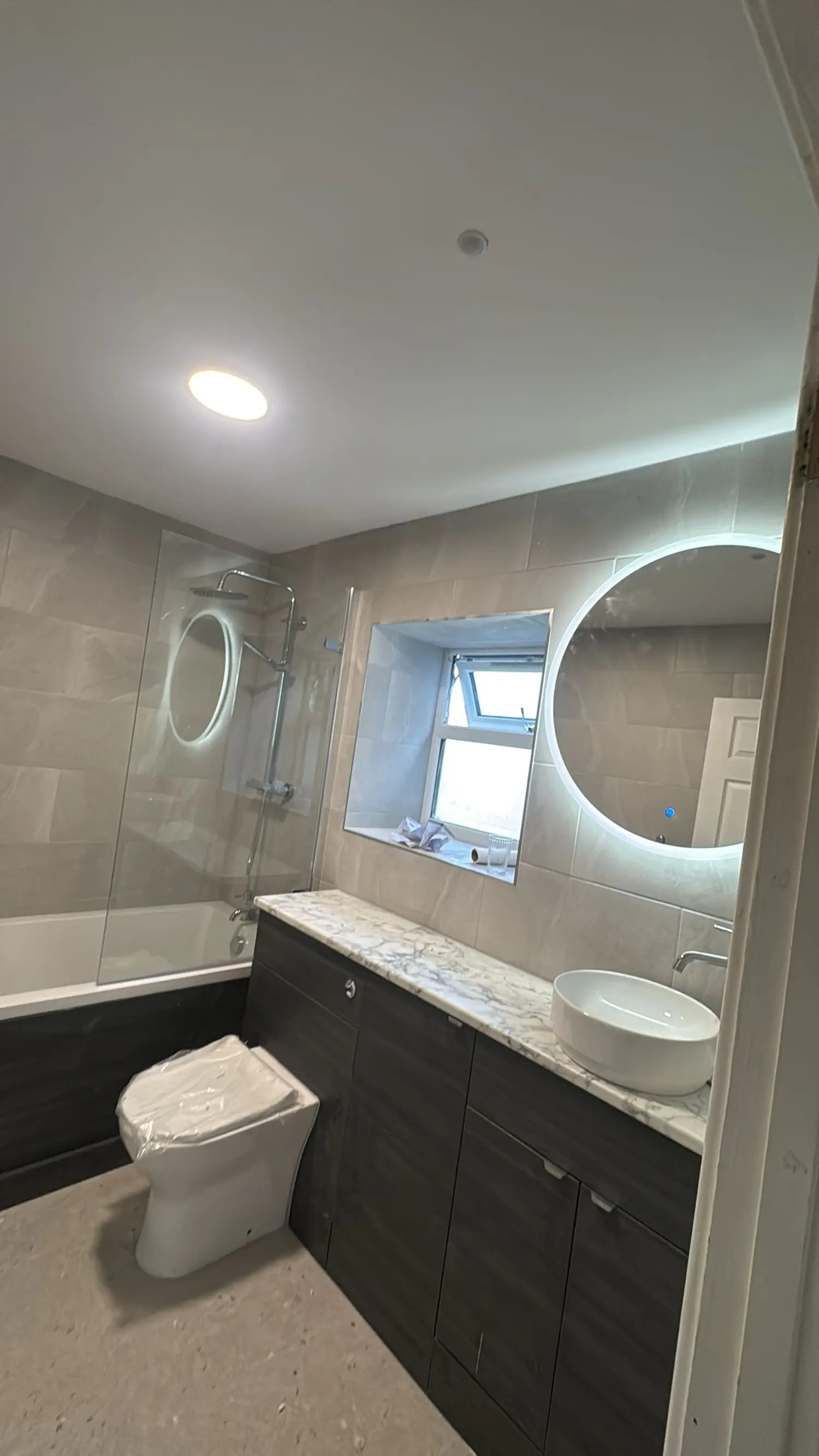 Bathroom with backlit mirror and recessed ceiling light