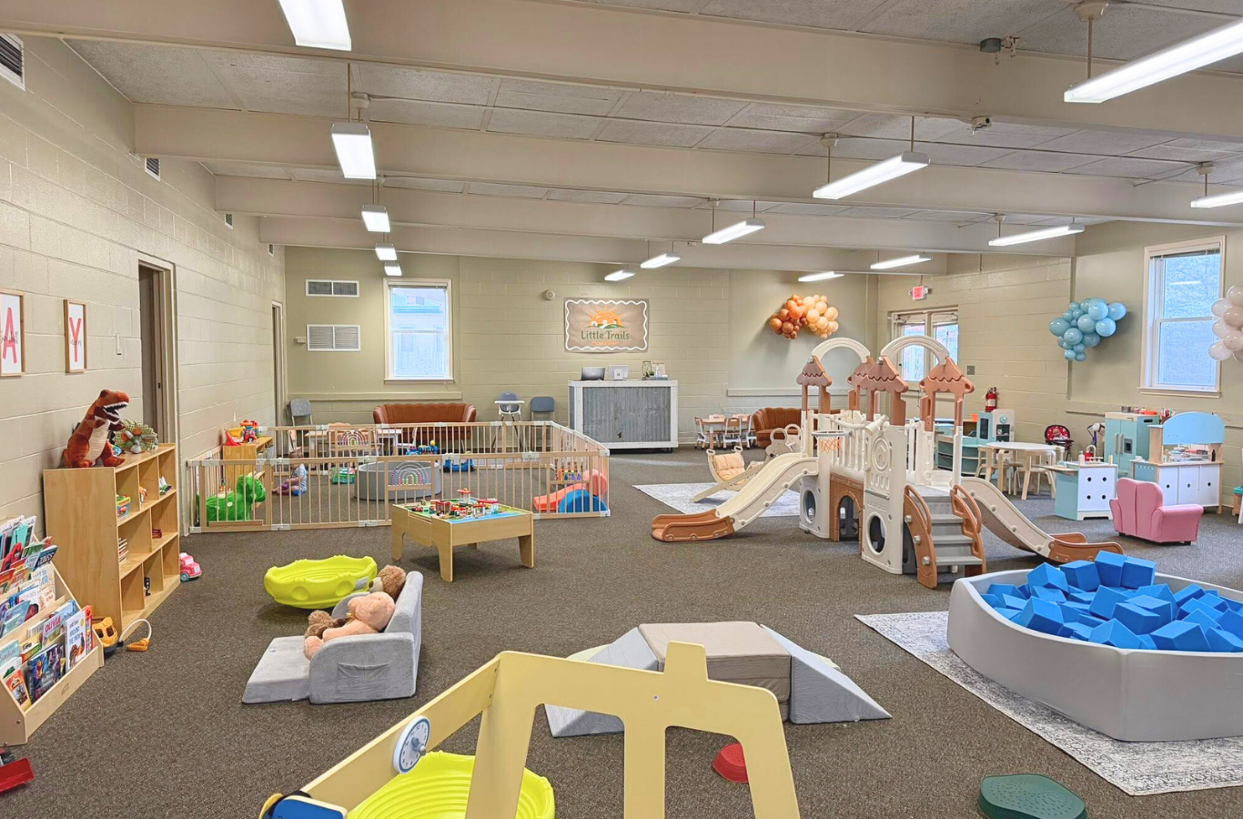 Wide shot of the Little Trails Playroom filled with families and children playing.
