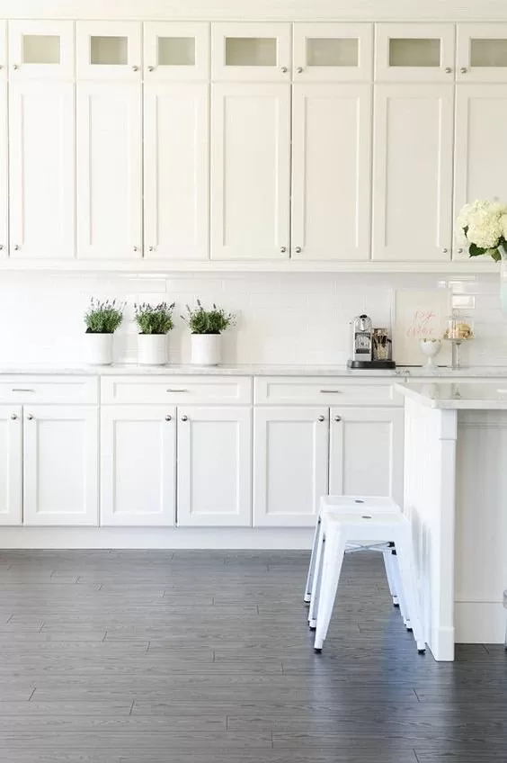 Bright white shaker kitchen with classic recessed-panel cabinets and gray flooring