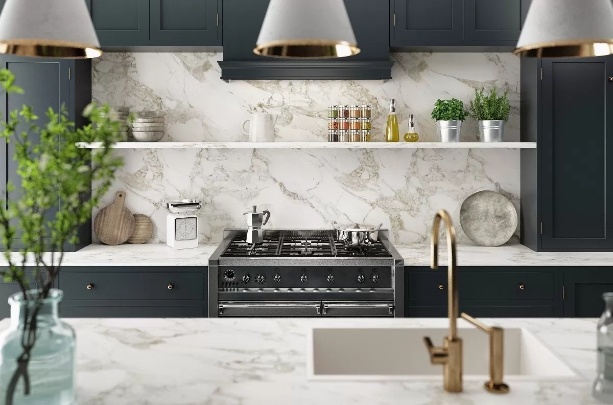 Distinctive Form quartz countertops with marble-look veining in a dark green kitchen with brass fixtures