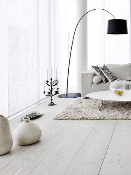 Bright living room with light wood flooring, a white sofa and a black arc floor lamp