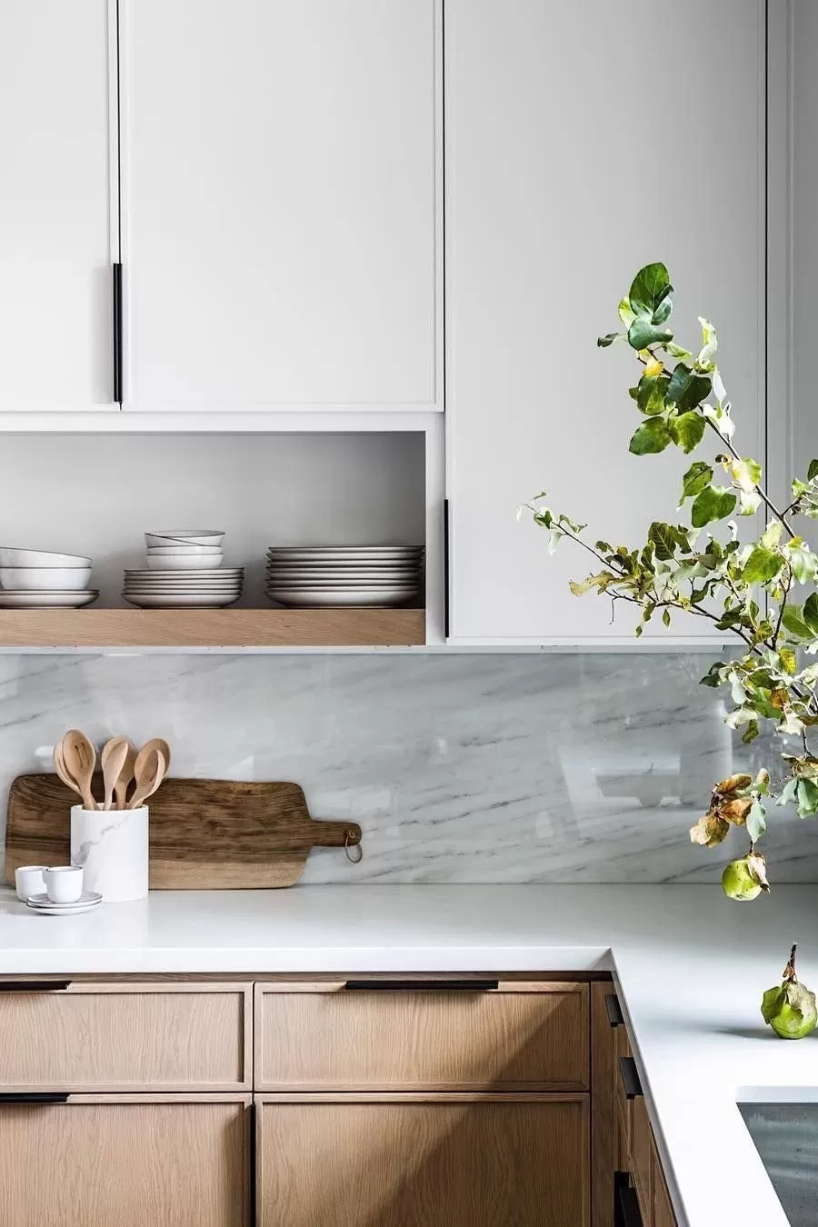 White and natural-wood kitchen with open shelving, stacked dishware and a marble backsplash