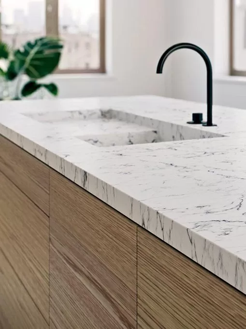 White quartz countertop with marble-look veining, wood cabinetry and a matte black faucet