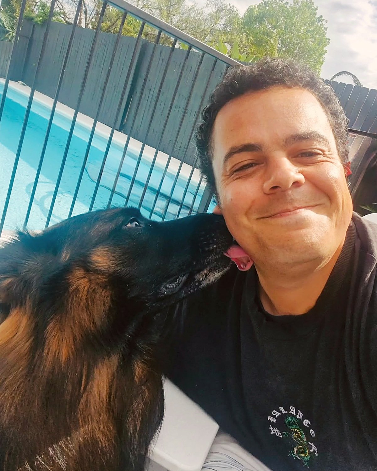 Marcus, canine care guide at Barc for Pets, getting a lick from a black and tan dog