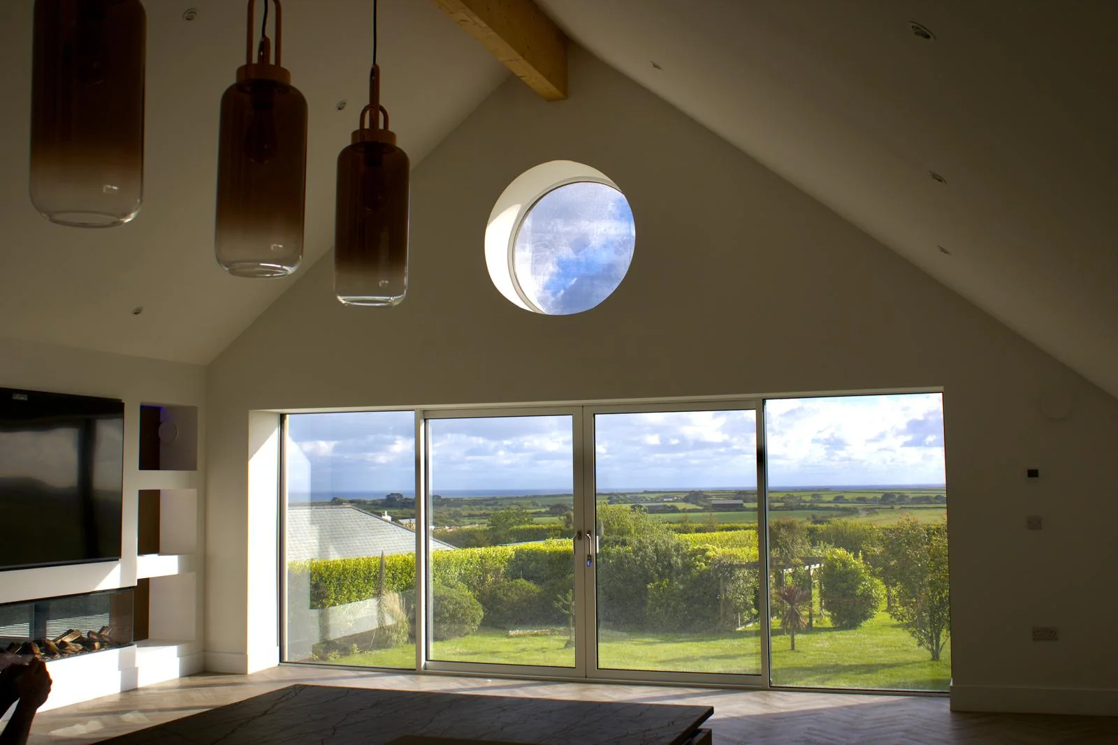 Premium Cornwall new build by L W Construction — open-plan living with feature round window
