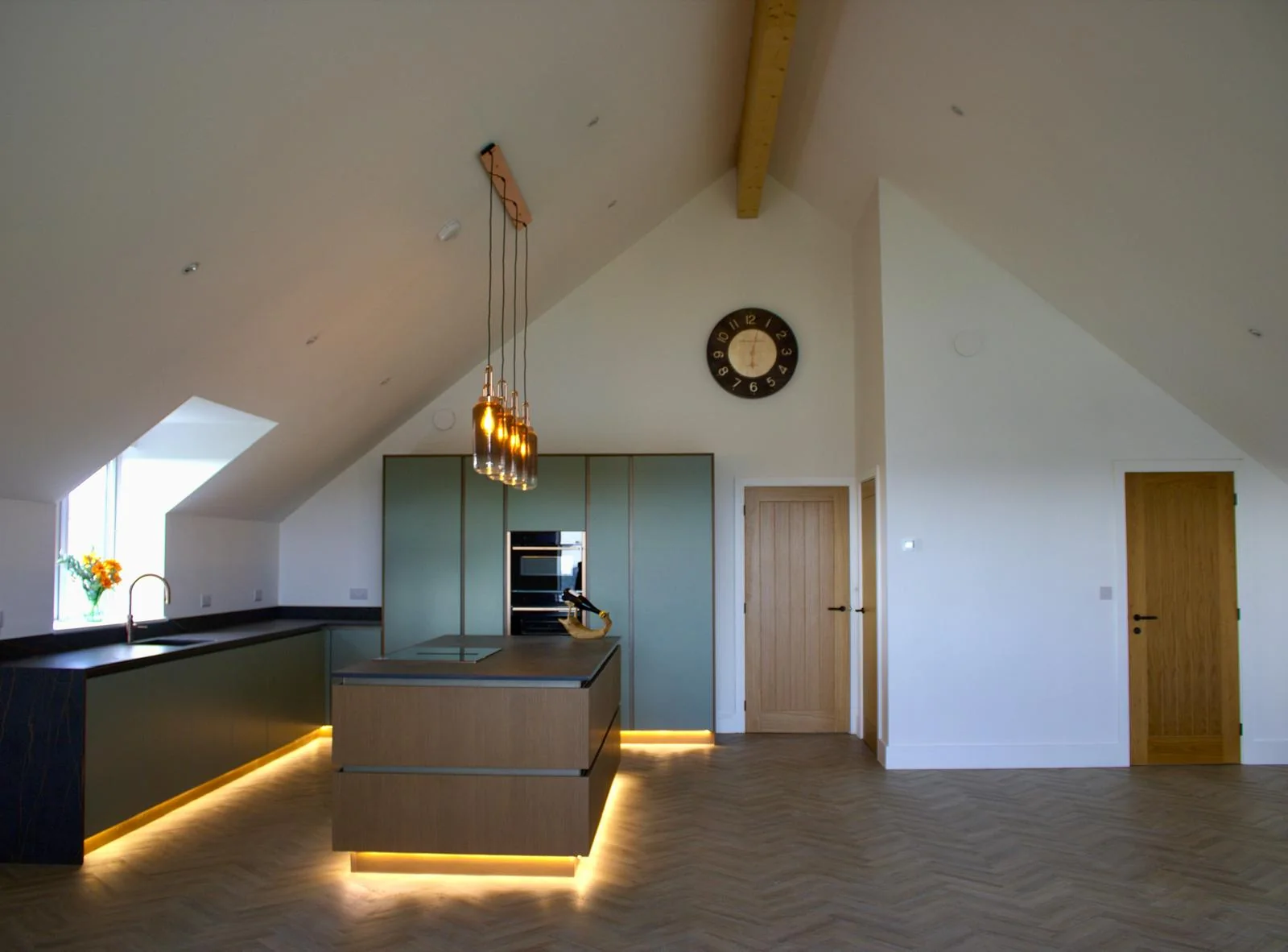 Premium Cornwall new build by L W Construction — vaulted open-plan kitchen with statement island lighting