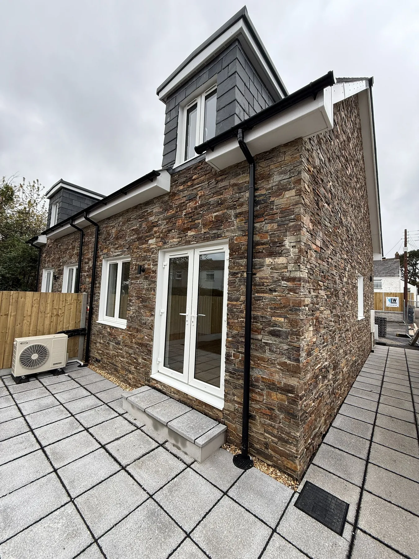 Recent new-build project by L W Construction in nearby Illogan (~2mi west of Camborne), Cornwall — side and rear elevation with patio