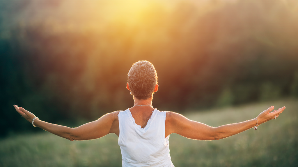 woman standing in a field with sunlight flare