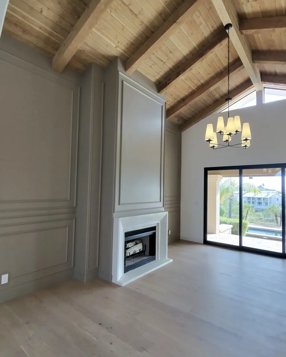 Finished living room with vaulted wood ceiling and painted paneled fireplace wall