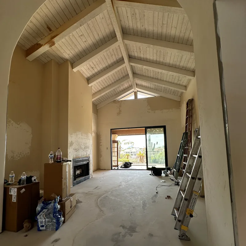 Vaulted living room in progress with patched walls and raw ceiling boards