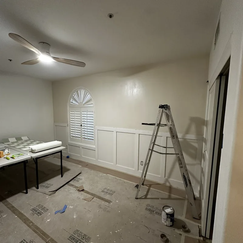 Bedroom prepped for wallpaper with ladder, table and floor protection
