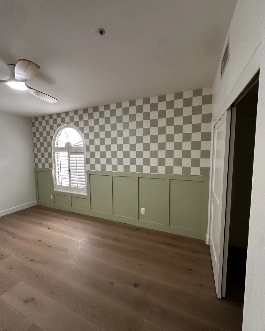 Bedroom finished with checkerboard wallpaper and green wainscot