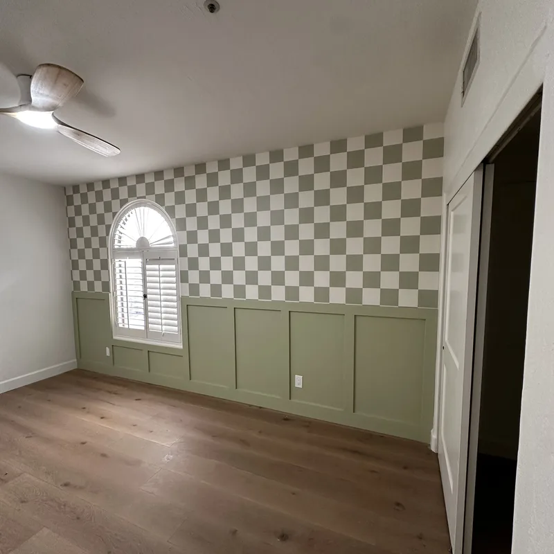 Checkerboard wallpaper above green wainscot paneling