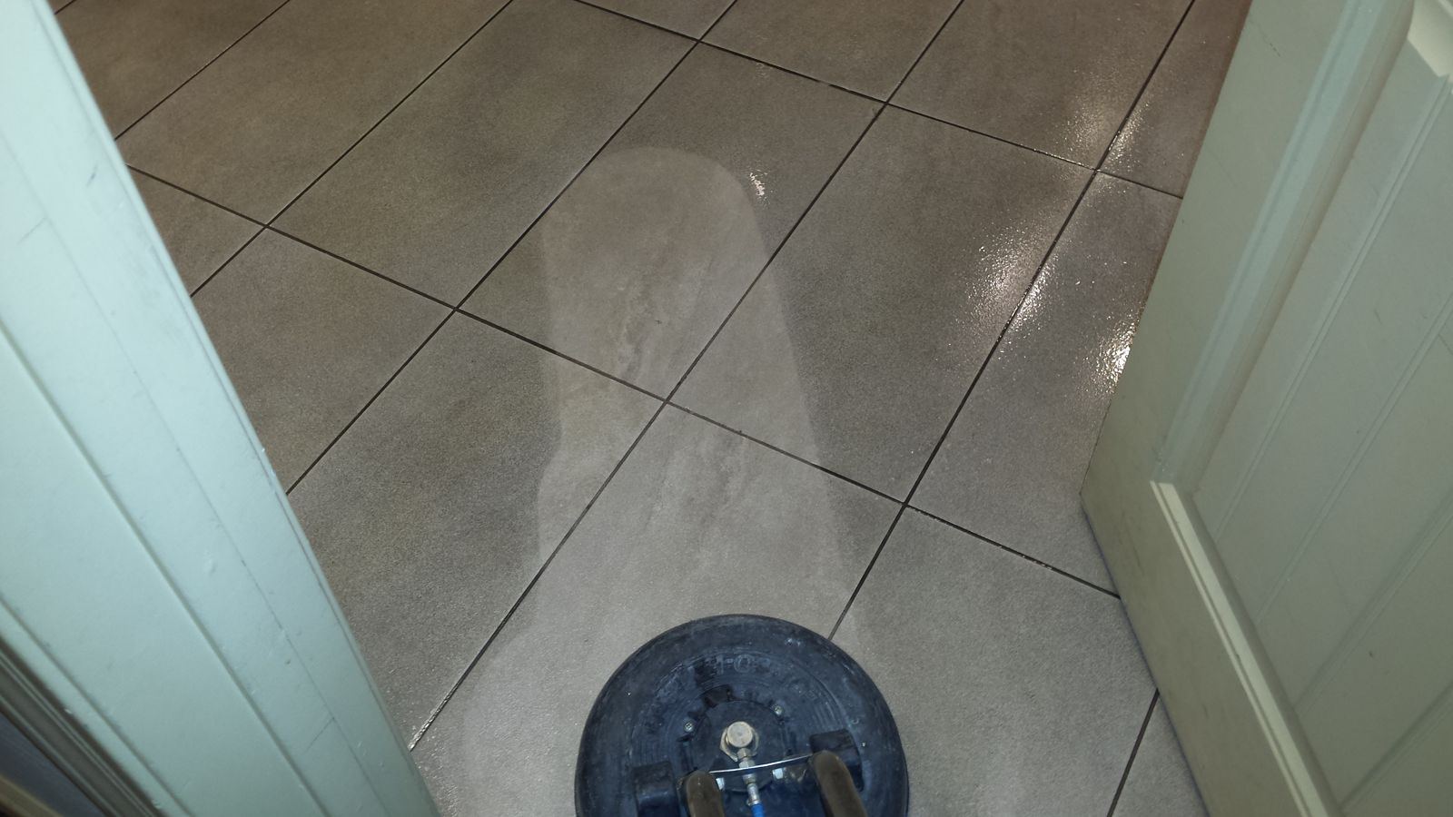 Grout being steam cleaned, clean strip visible